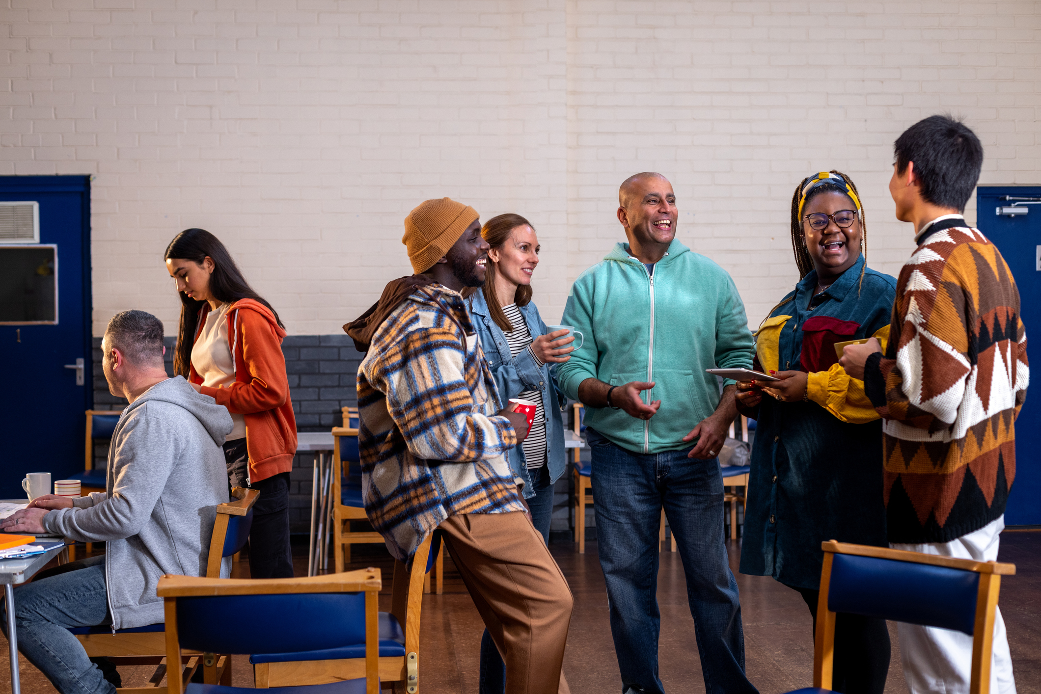 A group of people stands in a community centre talking.