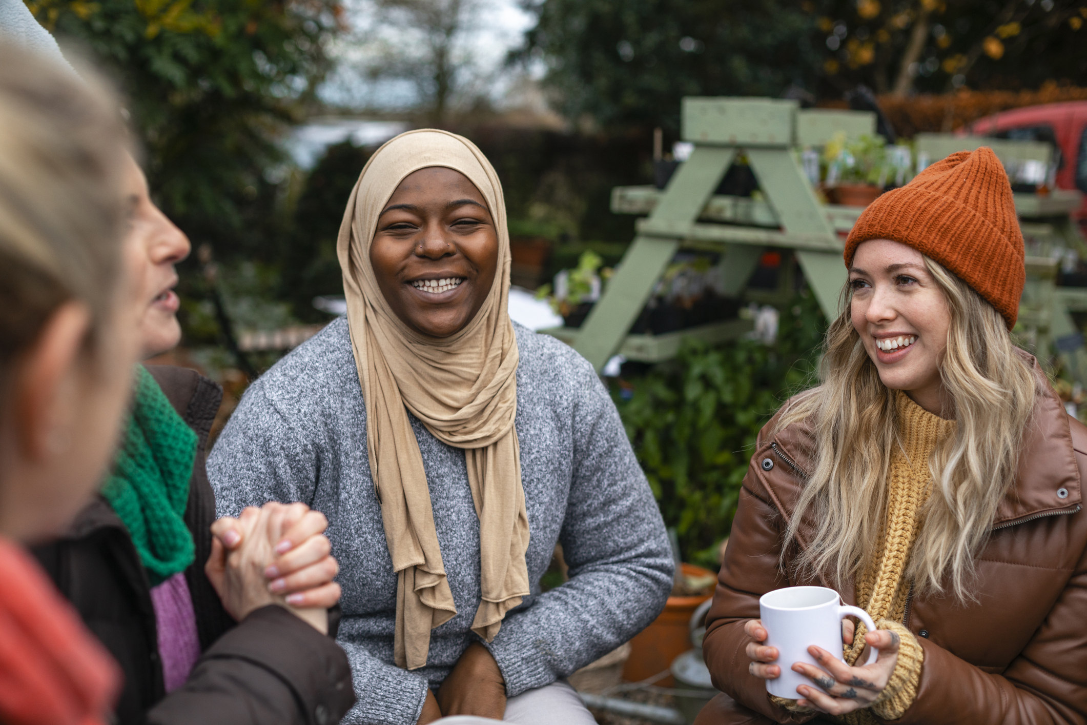 A group of women sitting outdoors, smiling and talking together.